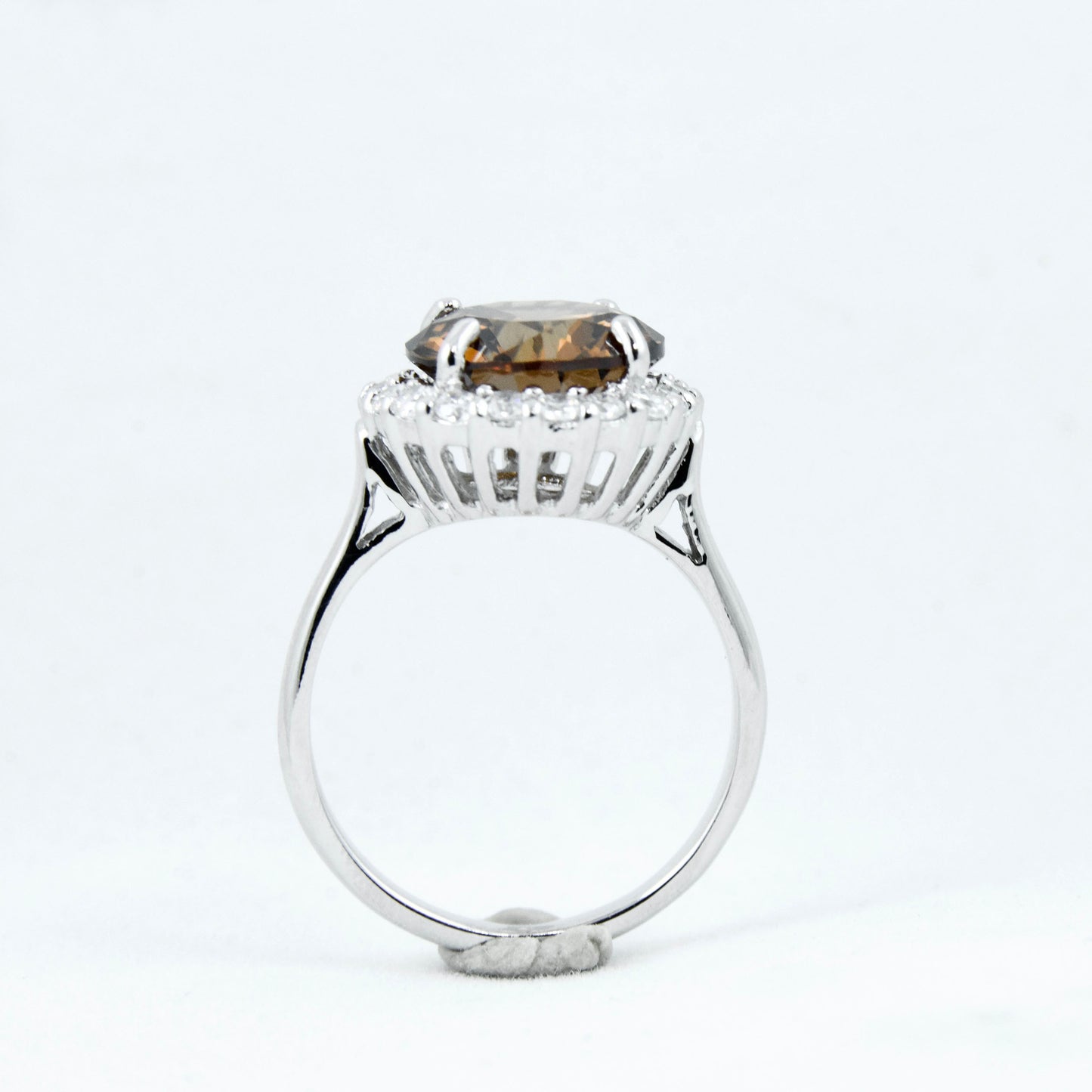 Non-tarnishing, rhodium plated, 925 sterling silver ring. Features a large coffee coloured round-cut centre AAA quality cubic zirconia stone surrounded by a halo of small clear cubic zirconia stones. Centre stone comes in two colours: black and coffee. Available in sizes 5, 6, 7, 8, and 9.