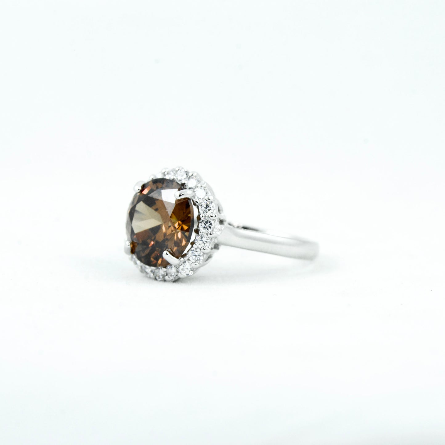 Non-tarnishing, rhodium plated, 925 sterling silver ring. Features a large coffee coloured round-cut centre AAA quality cubic zirconia stone surrounded by a halo of small clear cubic zirconia stones. Centre stone comes in two colours: black and coffee. Available in sizes 5, 6, 7, 8, and 9.