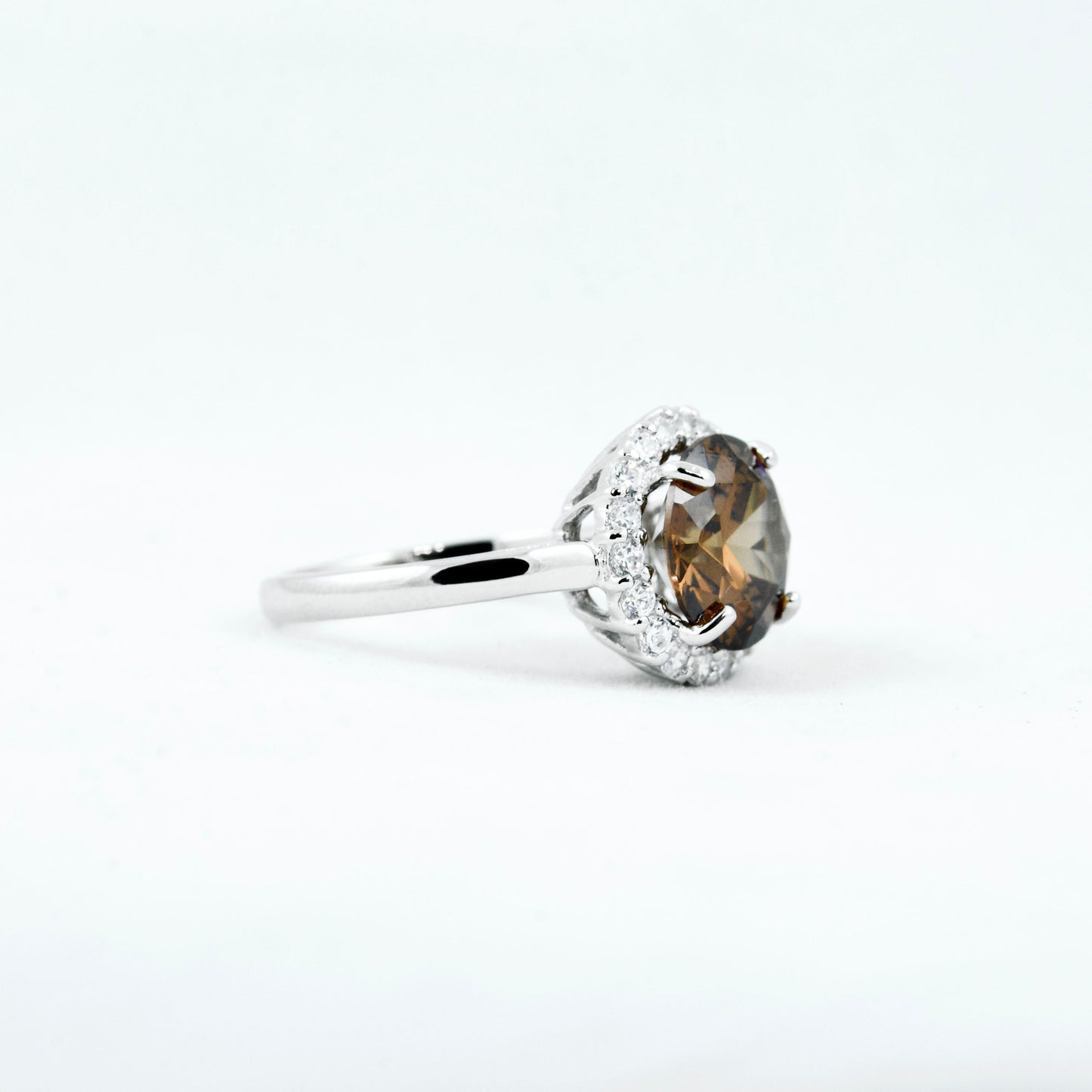 Non-tarnishing, rhodium plated, 925 sterling silver ring. Features a large coffee coloured round-cut centre AAA quality cubic zirconia stone surrounded by a halo of small clear cubic zirconia stones. Centre stone comes in two colours: black and coffee. Available in sizes 5, 6, 7, 8, and 9.