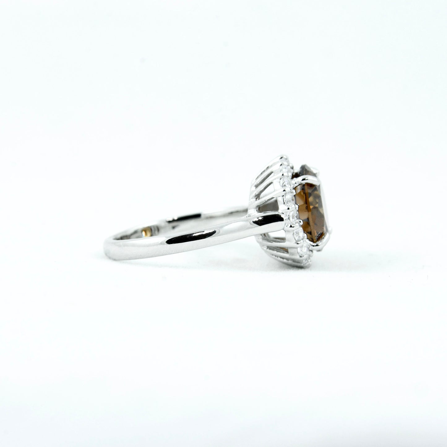 Non-tarnishing, rhodium plated, 925 sterling silver ring. Features a large coffee coloured round-cut centre AAA quality cubic zirconia stone surrounded by a halo of small clear cubic zirconia stones. Centre stone comes in two colours: black and coffee. Available in sizes 5, 6, 7, 8, and 9.